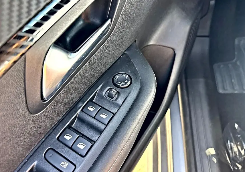 Gros plan sur la commande des vitres électriques et rétroviseurs côté conducteur de la Peugeot 208 gris artense.