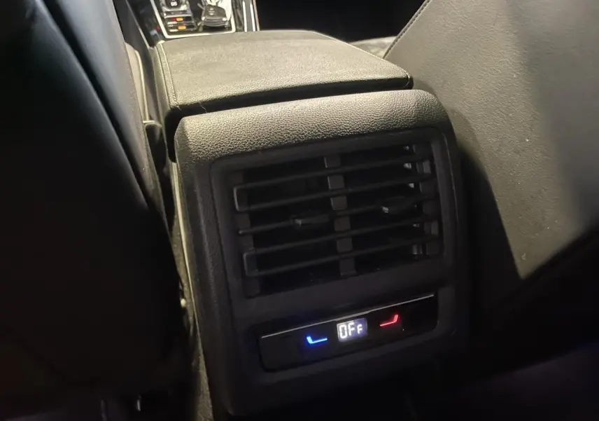 Détail de la console centrale arrière noire avec diffuseur d'air et commandes de siège chauffant éteintes sur Volkswagen Golf VIII R-Line.
