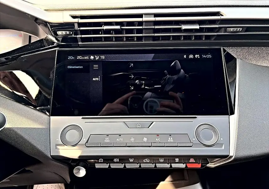 Vue rapprochée de la console centrale de la Peugeot 308 2025, écran tactile et commandes climatisation en noir et gris.