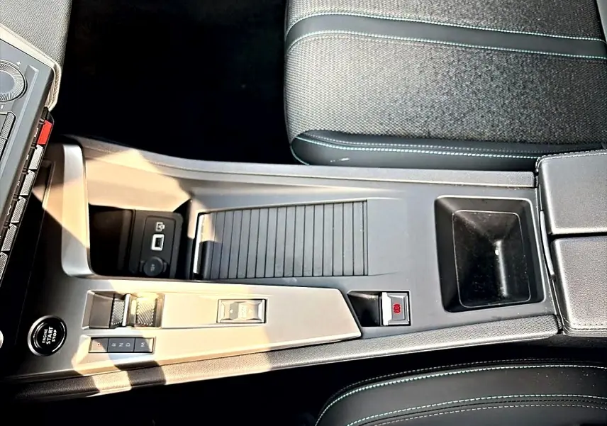 Vue plongeante sur la console centrale noire de la Peugeot 308 1.5 BlueHDi 130 Allure avec boîte auto et accoudoir.