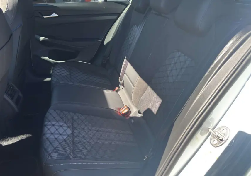 Vue intérieure côté droit sur la banquette arrière en tissu noir à motifs géométriques d'une Volkswagen Golf blanc oryx.