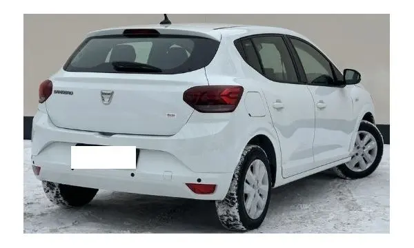 Vue 3/4 arrière droite d'une Dacia Sandero 2023 Blanc Glacier, compacte avec feux arrière rouges et jantes blanches sur neige.