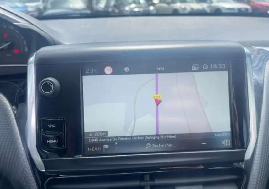 Vue rapprochée de l’écran tactile de navigation 3D de la Peugeot 208 blanche perle, avec commandes latérales visibles.