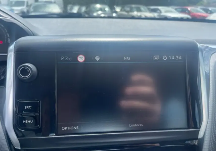Écran tactile central de la Peugeot 208 blanc perle, vue frontale du tableau de bord avec commandes SRC et MENU.