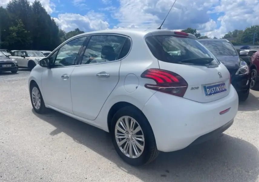 Peugeot 208 blanc perle vue 3/4 arrière droit, avec jantes alliage 16 pouces et feux arrière distinctifs.