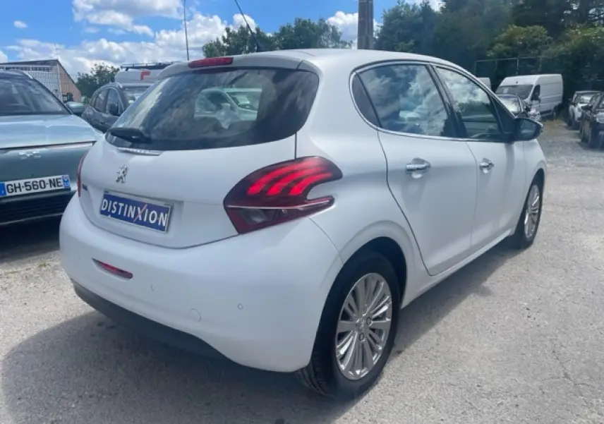 Vue 3/4 arrière droite d'une Peugeot 208 blanche perle avec jantes alliage et feux arrière distinctifs.