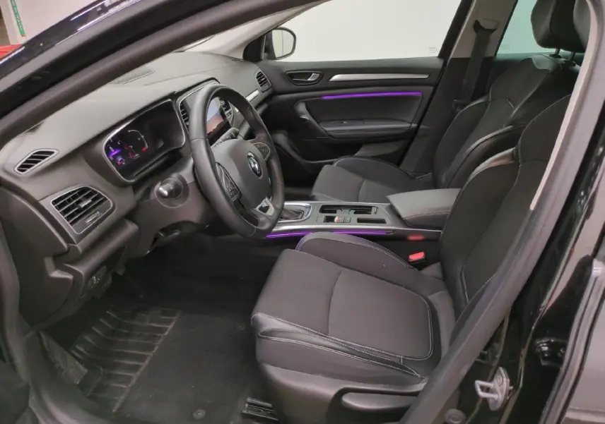 Intérieur avant droit de la Renault Mégane noire, avec sièges tissu noir et éclairage d'ambiance violet sur la porte et console.