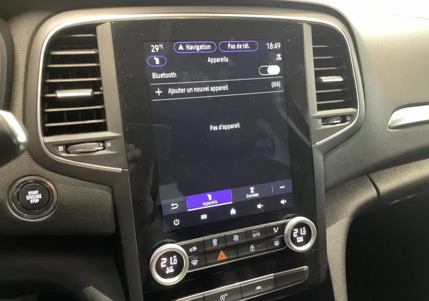Vue rapprochée de la console centrale noire de la Renault Mégane 2023 avec écran tactile et commandes de climatisation.