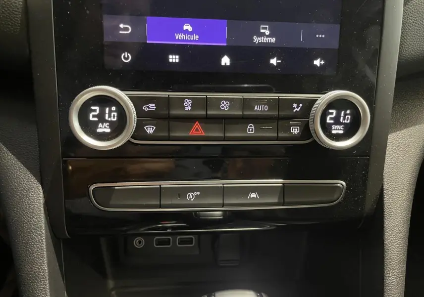 Vue rapprochée de la console centrale de la Renault Mégane noire, avec commandes climatisation bi-zone et prises USB visibles.