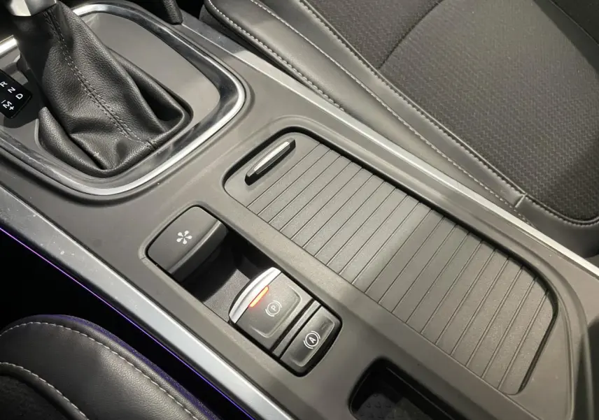 Vue rapprochée de la console centrale noire avec frein de parking électrique et sellerie tissu gris de la Renault Mégane 2023.