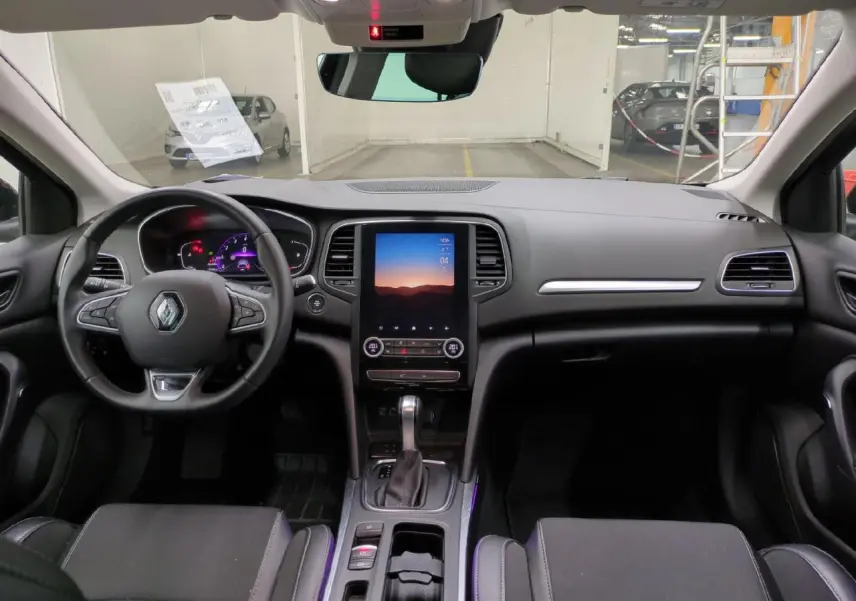 Vue intérieure avant de la Renault Mégane 2023, tableau de bord noir avec écran tactile vertical et volant multifonction.