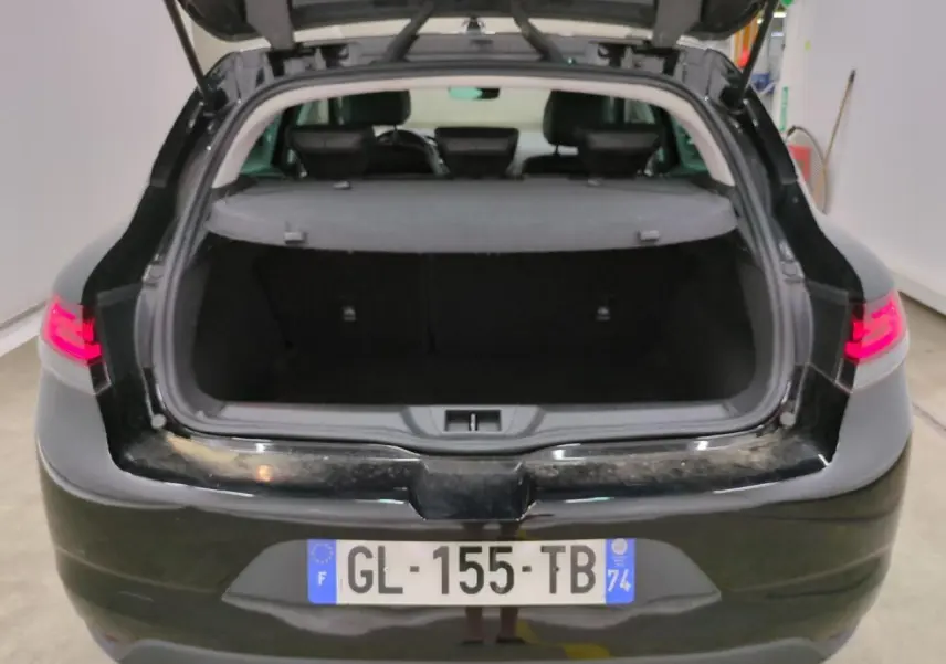Vue arrière ouverte de la Renault Mégane noire métal 2023, coffre spacieux et feux arrière LED allumés.