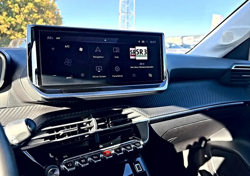 Vue intérieure du tableau de bord de la Peugeot 208 1.2 100 allure, écran tactile central et commandes piano visibles.
