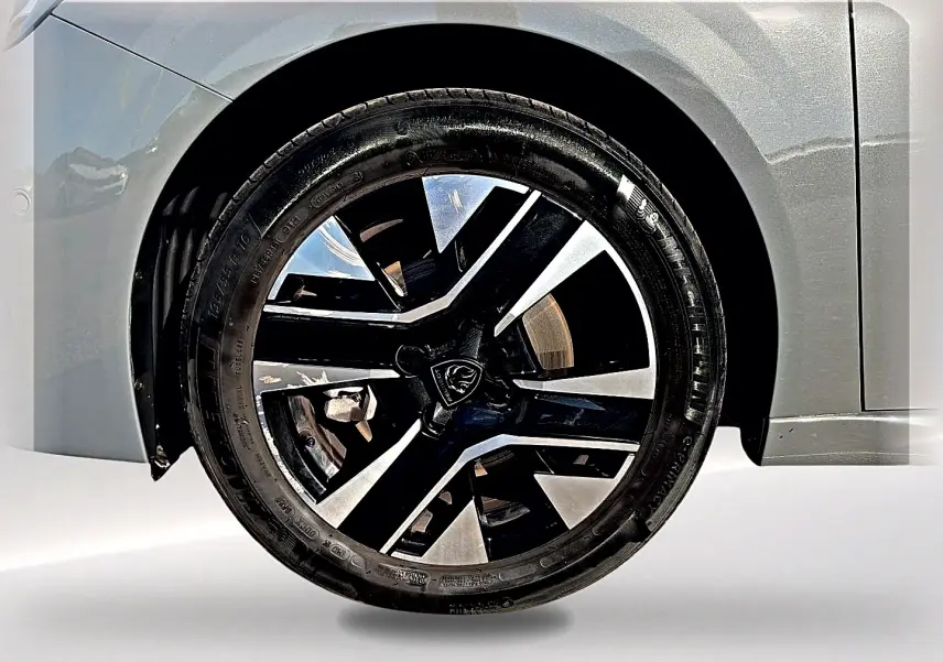 Gros plan sur la jante alu noire et argentée du côté avant gauche d'une Peugeot 208 gris selenium.