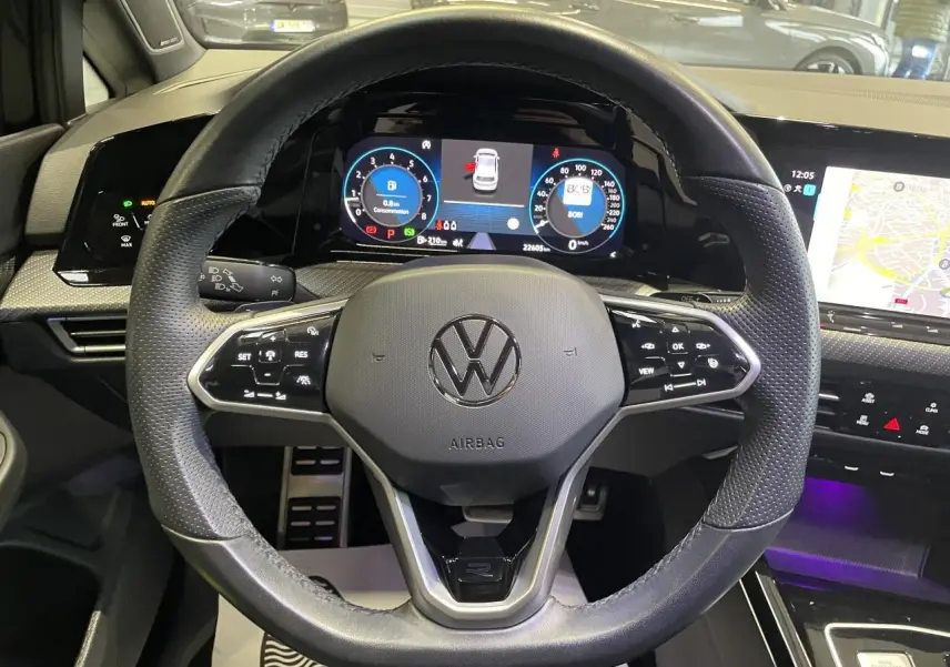 Vue intérieure centrée sur le volant cuir multifonctions noir avec tableau de bord digital et écran tactile de la Volkswagen Golf VIII R-Line Black.