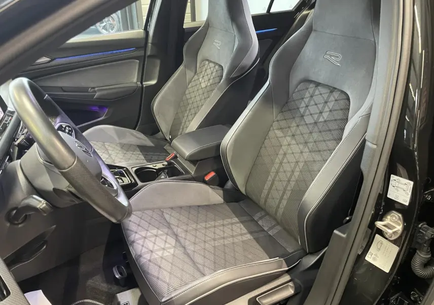Vue intérieure côté conducteur de la Volkswagen Golf VIII R-Line Black avec sièges sport gris et détails carbone.