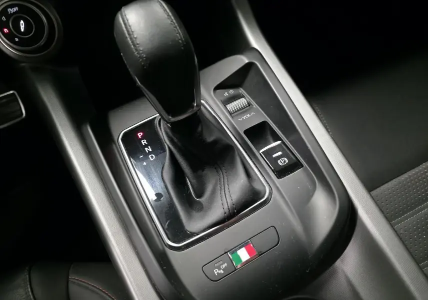 Gros plan sur la console centrale de l'Alfa Romeo Tonale 2024, levier de vitesse cuir noir et drapeau italien.