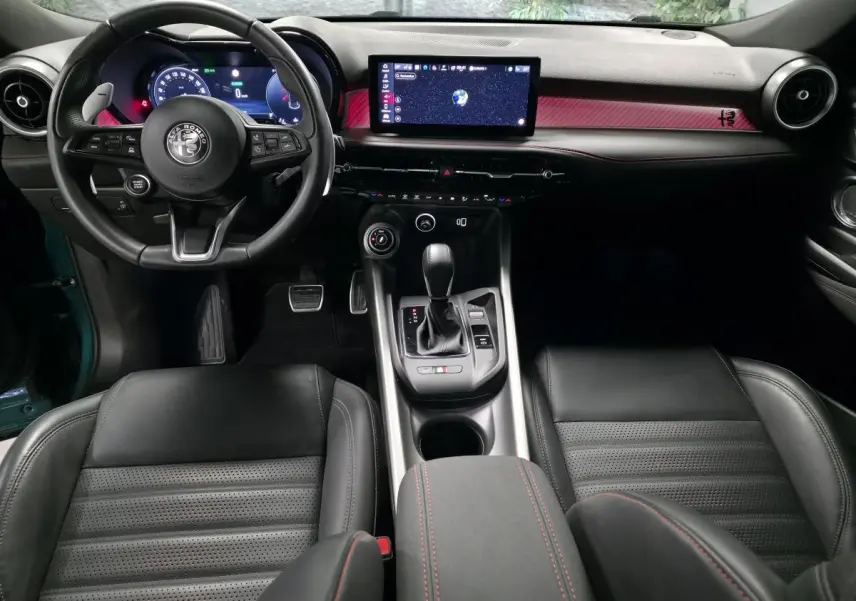 Vue intérieure centrée sur le tableau de bord et console d'une Alfa Romeo Tonale 2024, sellerie cuir noir et détails rouges.