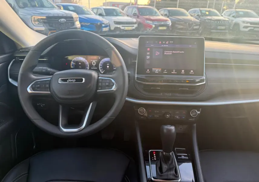 Vue intérieure frontale du tableau de bord du Jeep Compass bleu 2024 avec écran tactile et volant multifonction.