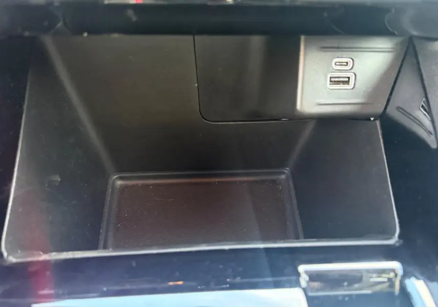 Gros plan sur la console centrale noire du Jeep Compass 2024, avec prises USB visibles dans un compartiment vide.