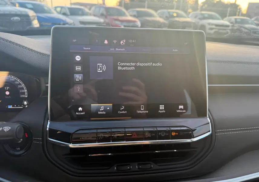 Vue intérieure centrée sur l'écran tactile multimédia du Jeep Compass 2024 avec tableau de bord noir et commandes visibles.
