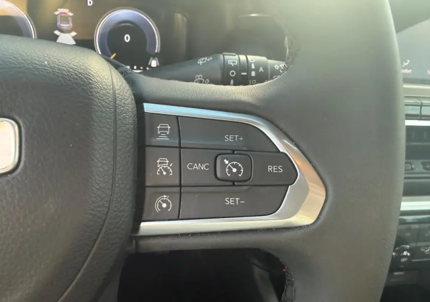 Gros plan sur les commandes du régulateur de vitesse au volant du Jeep Compass bleu 2024, intérieur moderne et fonctionnel.