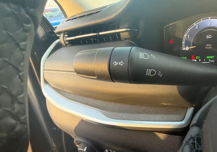 Gros plan sur la commande des clignotants et phares du tableau de bord du Jeep Compass bleu 2024, intérieur noir.