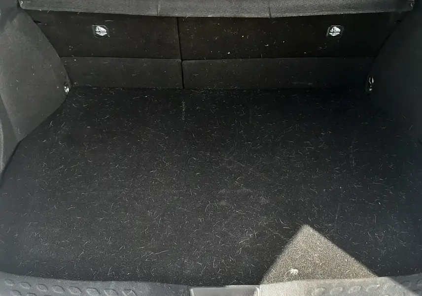 Coffre ouvert vu de face du Toyota C-HR 1.8 Hybrid 122 Design noir, montrant un espace de chargement vide et propre.