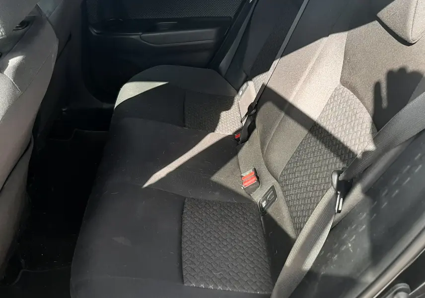 Vue intérieure côté droit des sièges arrière noirs en tissu du Toyota C-HR 1.8 Hybrid 2023 avec ceinture de sécurité visible.