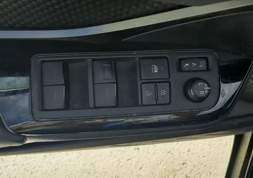 Vue rapprochée des commandes de lève-vitres et rétroviseurs sur la porte côté gauche du Toyota C-HR noir 2023.