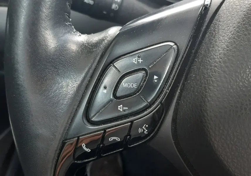 Gros plan sur les commandes multifonctions noires du volant côté gauche du Toyota C-HR 1.8 Hybrid 2023.