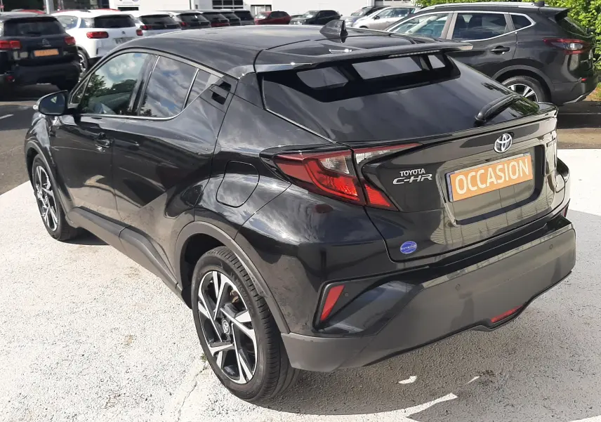 Vue 3/4 arrière droite d'un Toyota C-HR noir 2023 avec jantes alliage bicolores et toit surélevé.
