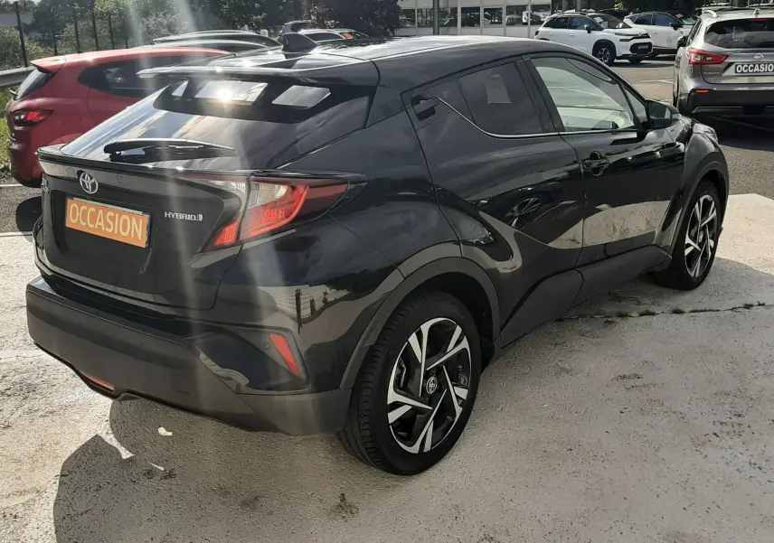 Toyota C-HR 1.8 Hybrid noir en 3/4 arrière droit, avec jantes bi-ton et feux arrière LED distinctifs.