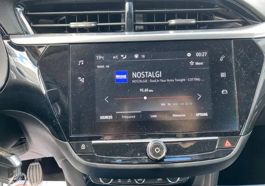 Gros plan sur l'écran tactile central noir de l'Opel Corsa 1.2i Turbo 2021, affichant la radio FM Nostalgie.