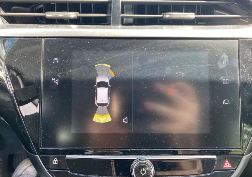 Écran tactile central de l’Opel Corsa 1.2i Turbo 2021 affichant l’aide au stationnement avec capteurs avant et arrière.