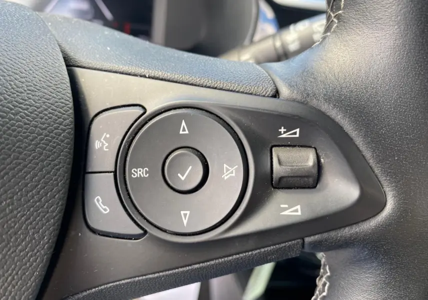 Gros plan sur les commandes gauche du volant en cuir noir de l’Opel Corsa 1.2i Turbo 2021, boutons multifonctions.