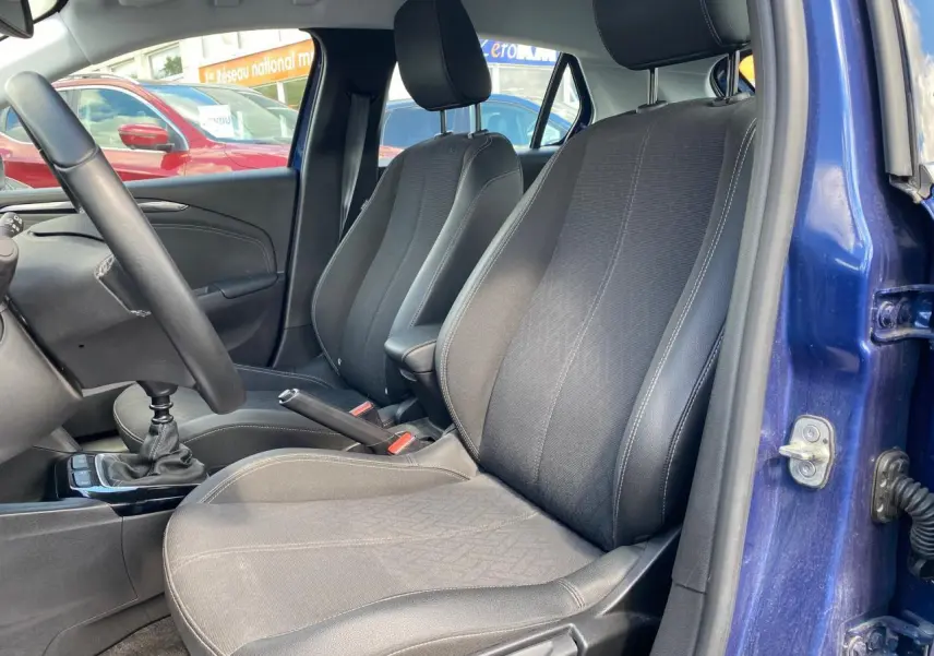 Vue intérieure côté conducteur de l’Opel Corsa bleu nautique, montrant les sièges avant et le levier de vitesse manuel.