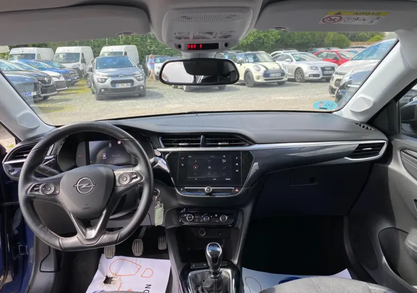 Vue intérieure avant de l’Opel Corsa bleu nautique, montrant le volant cuir multifonction et l’écran digital central.