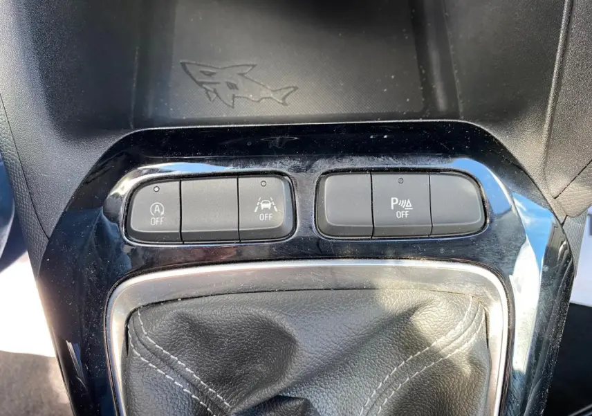 Gros plan sur la console centrale de l’Opel Corsa bleu nautique, montrant le soufflet de levier de vitesse et les boutons de contrôle.