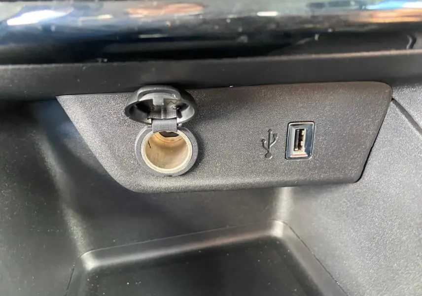 Gros plan sur la prise 12V et port USB intégrés dans la console centrale de l’Opel Corsa 1.2i Turbo.