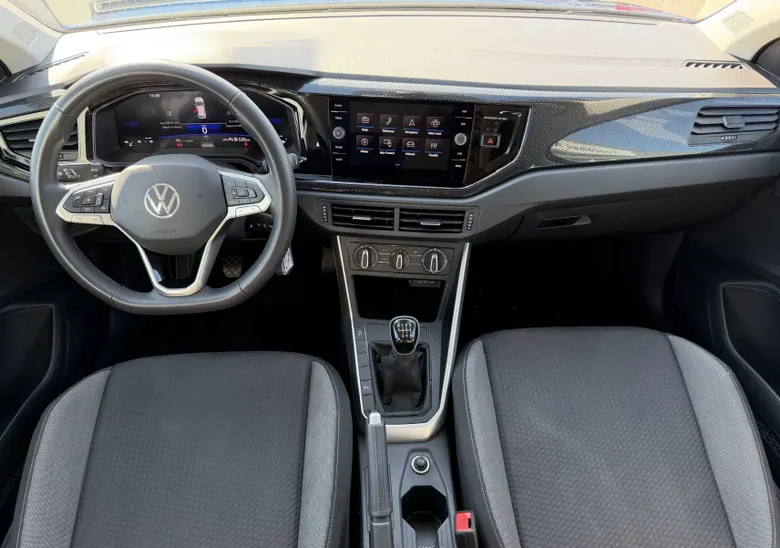 Vue intérieure avant du Volkswagen Taigo 1.0 TSI 116 BVM6 2025, tableau de bord noir avec volant cuir multifonction et levier manuel.
