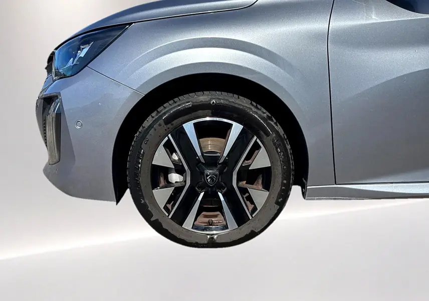 Gros plan sur la roue avant gauche et l'aile avant gris artense de la Peugeot 208 1.2 100 allure 2025.