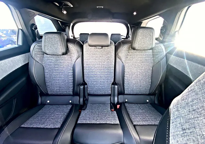 Vue intérieure des trois sièges arrière en tissu gris et cuir noir du Peugeot 5008 Hybrid 145 allure e-dcs6 blanc.