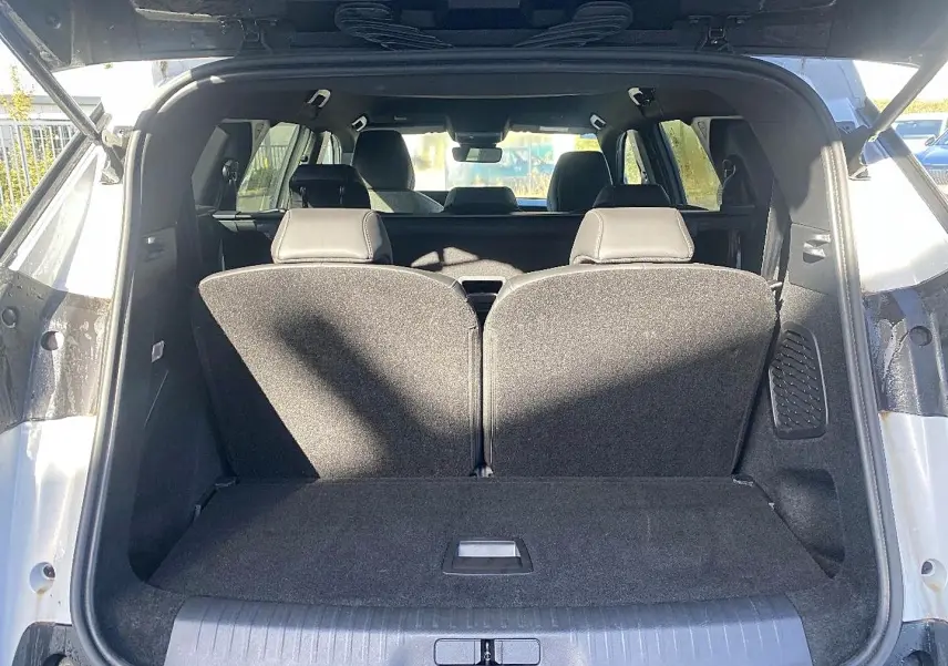 Coffre ouvert d’un Peugeot 5008 blanc, vue arrière montrant les sièges rang 3 relevés et l’habitacle intérieur.