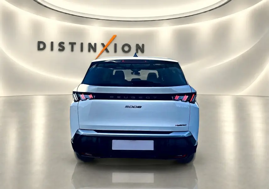 Vue arrière d'un Peugeot 5008 blanc hybride 2025 dans un showroom lumineux avec logo Distinxion en arrière-plan.