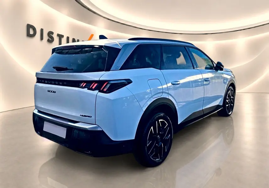 Vue 3/4 arrière droite d’un Peugeot 5008 Hybrid blanc avec jantes noires et feux arrière LED distinctifs.