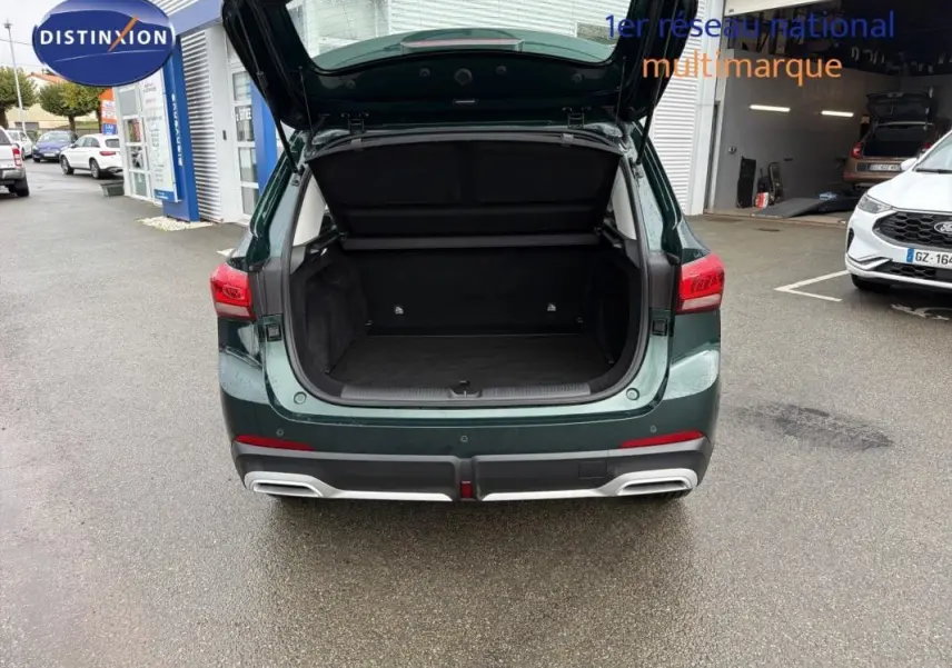 Vue arrière du MG MOTOR ZS vert foncé 2026 avec coffre ouvert, montrant l’espace de chargement vide.