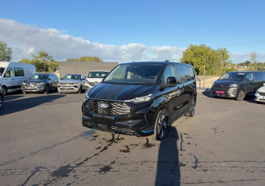 Ford Transit Fourgon Custom noir vu de 3/4 avant droit sur un parking en extérieur, avec jantes alliage sport.