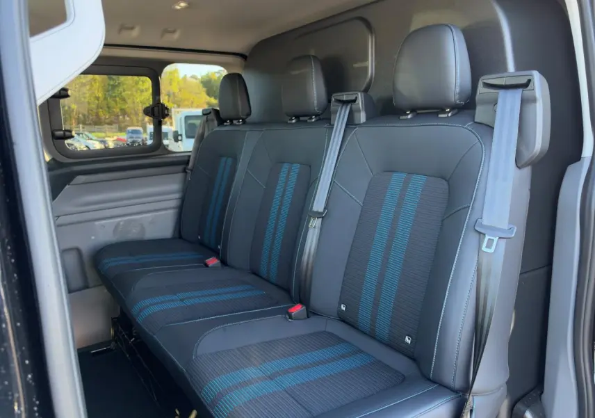 Vue intérieure côté droit du Ford Transit Fourgon 2026, banquette arrière noire avec bandes bleues et ceintures grises.