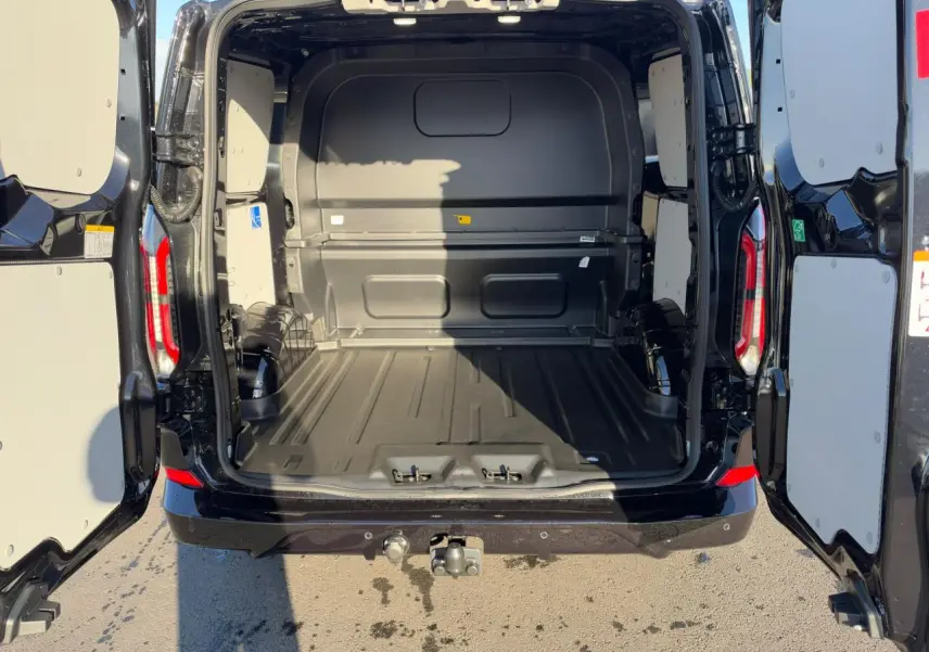 Vue arrière du Ford Transit Fourgon noir 2026 avec portes ouvertes et espace de chargement vide, crochet d'attelage visible.